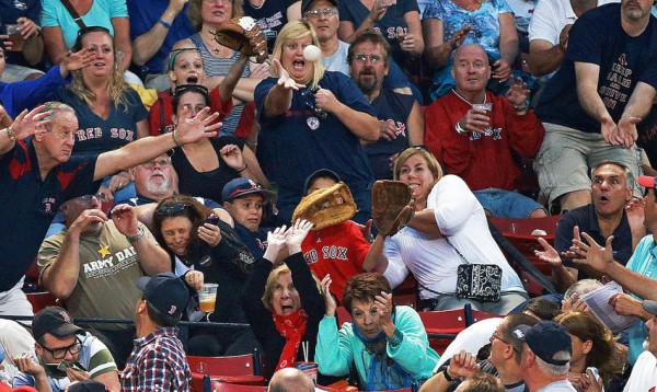 Réaction de fans de baseball essayant d'attraper la balle, en août à Fenway Park
