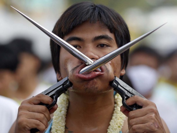 Devotee of the Chinese Bang Neow Shrine with spikes attached to plastic pistols pierced through his cheeks takes part in a procession celebrating the annual vegetarian festival in Phuket