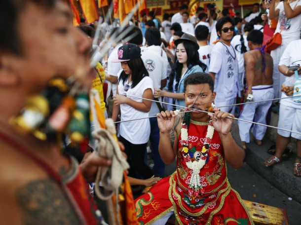 Devotees of the Chinese Bang Neow Shrine with different objects pierced through their mouths get ready for a procession celebrating the annual vegetarian festival in Phuket