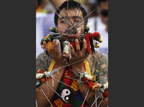 A devotee of the Chinese Bang Neow Shrine with many spikes pierced through his cheeks and skin, takes part in a street procession celebrating the annual vegetarian festival in Phuket