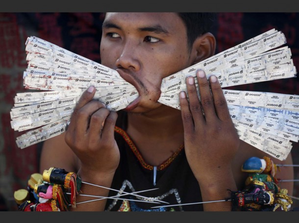 A devotee of Ban Tha Rua Chinese shrine with his cheeks pierced with razor blades takes a part in street procession celebrating the annual vegetarian festival in Phuket