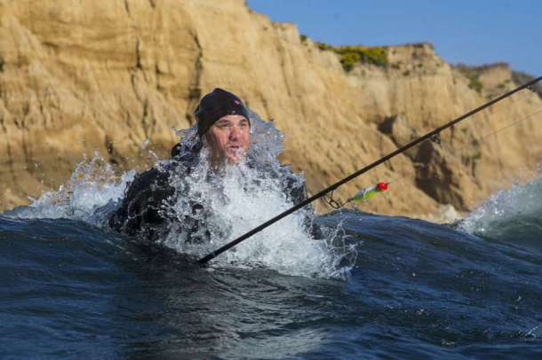 Chris Buchta, un pêcheur surfeur, qui essaye d’attraper un bar rayé dans Montauk Point, New York.