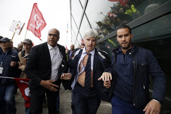TOPSHOTS Director of Air France in Orly Pierre Plissonnier, nearly shirtless, runs away from the demonstrators, helped by security officers, after several hundred of employees invaded the offices of Air France, interrupting the meeting of the Central Committee (CCE) in Roissy-en-France, on October 5, 2015. Air France-KLM unveiled a revamped restructuring plan on October 5 that could lead to 2,900 job losses after pilots for the struggling airline refused to accept a proposal to work longer hours. AFP PHOTO / KENZO TRIBOUILLARD