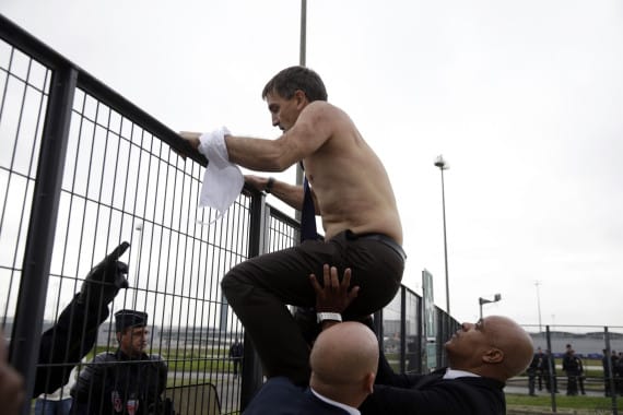 Human Resources Director of Air France Xavier Broseta, shirtless, tries to cross a fence, helped by security and police officers, after several hundred of employees invaded the offices of Air France, interrupting the meeting of the Central Committee (CCE) in Roissy-en-France, on October 5, 2015. Air France-KLM unveiled a revamped restructuring plan on October 5 that could lead to 2,900 job losses after pilots for the struggling airline refused to accept a proposal to work longer hours. AFP PHOTO / KENZO TRIBOUILLARD