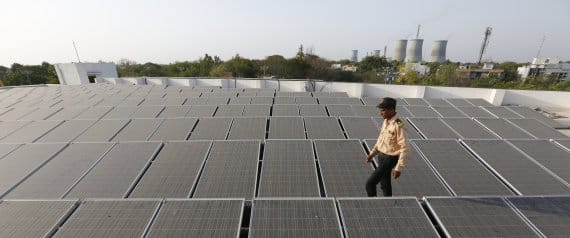 An Indian security man walks amid rooftop solar plant at the secretariat gymkhana in Gandhinagar, India, Tuesday, May 17, 2016. (AP Photo/Ajit Solanki)