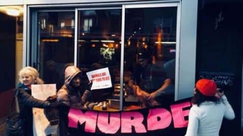 un cuisinier prépare de la viande devant des végans