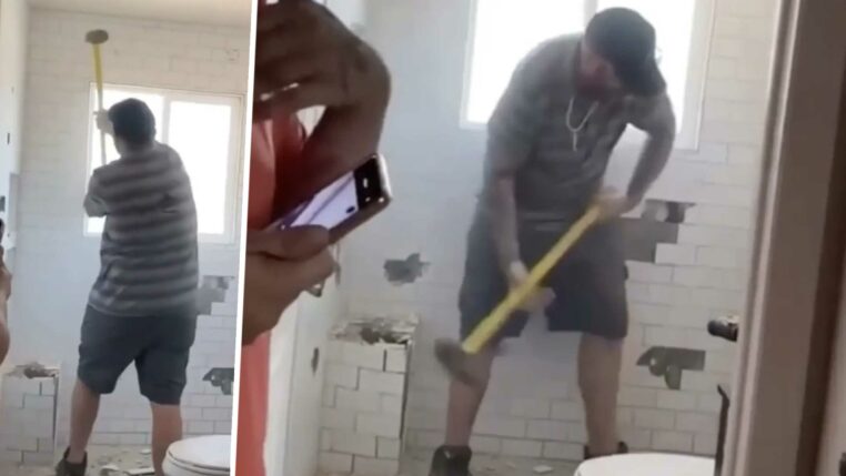 un ouvrier casse la salle de bain qu'il a construite