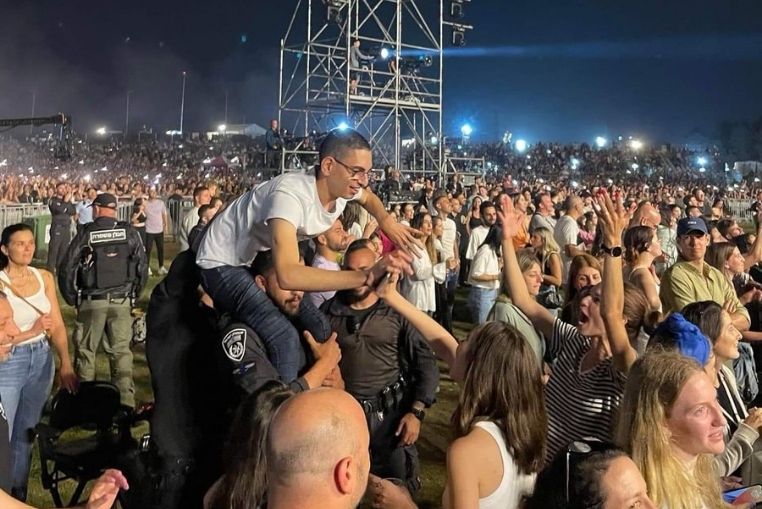 un policier prend un handicapé sur ses épaules dans un concert