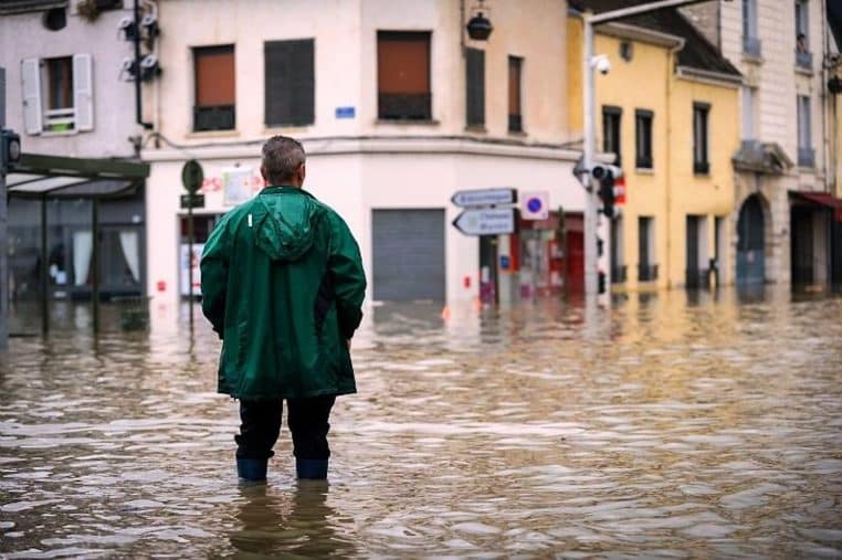 Individu en vêtements de pluie, marchand dans des rues inondées.