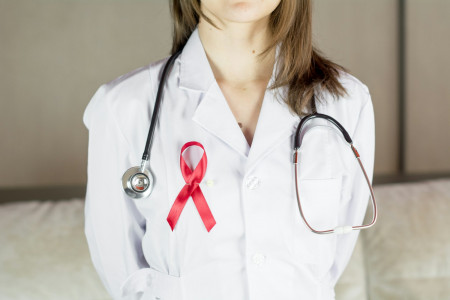 a female doctor wearing a red ribbon and a stethoscope, révolution médicale sida