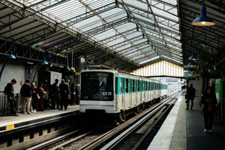 A busy Paris metro station with a vintage train arriving as passengers wait on the platform.