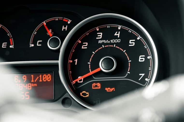 Detailed view of a car dashboard featuring tachometer, odometer, and various indicators.