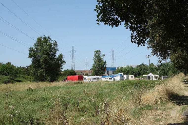 Rangée de caravanes et roulottes devant un mur bétonné en zone urbaine