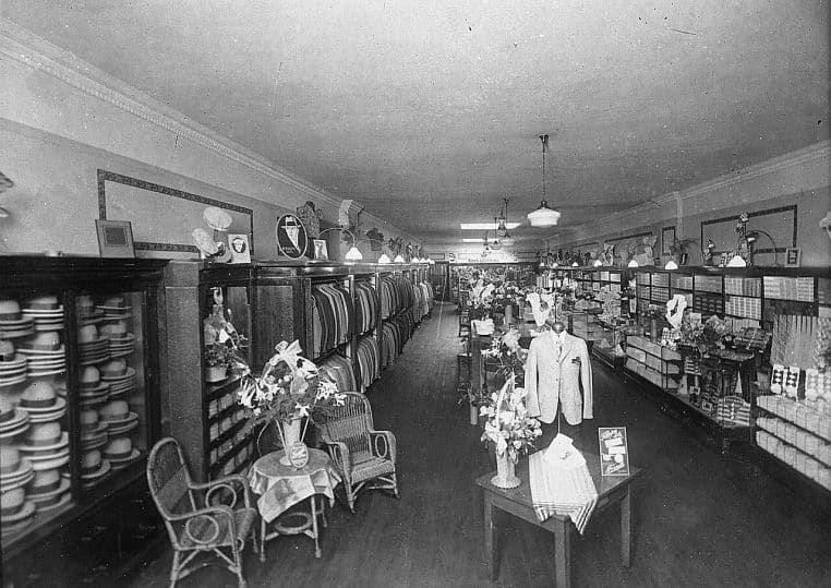 Intérieur ancien d’une boutique de vêtements avec mannequins et rayonnages.