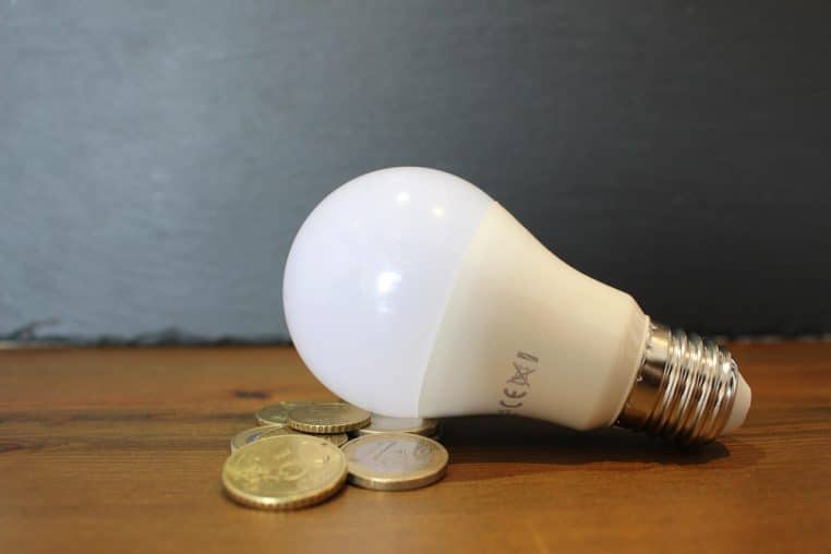 Ampoule LED et pièces de monnaie illustrant le coût de l’électricité.
