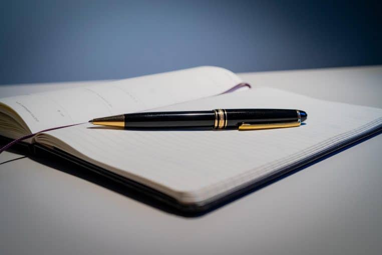 Gros plan sur un stylo à bille posé sur un calendrier papier.