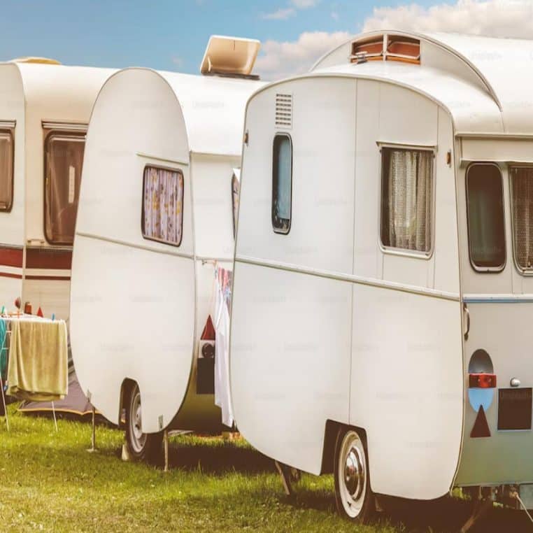 Trois caravanes vintage alignées devant un ciel bleu