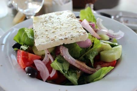 Assiette de salade grecque colorée garnie de feta, tomates cerises, concombres et olives noires.