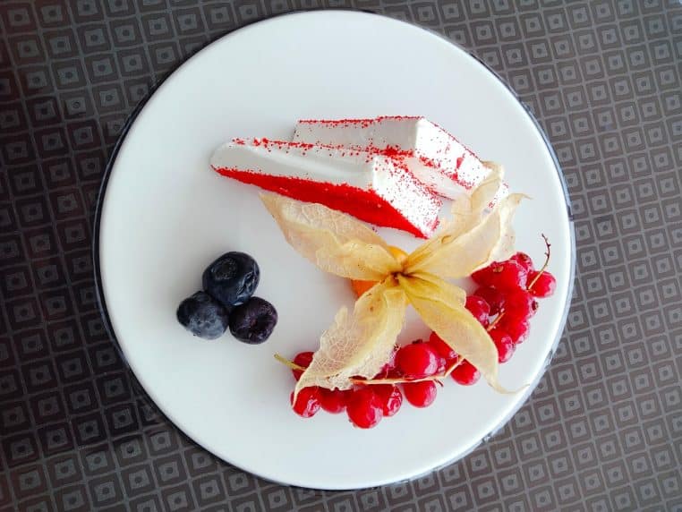 Wedge de feta agrémentée de baies fraîches posée sur un support sombre.