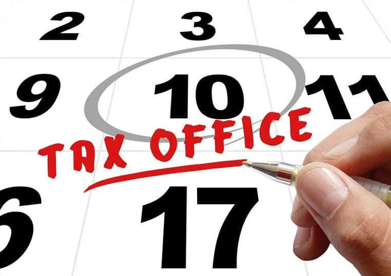 Illustration d’une main écrivant sur un document devant un calendrier.