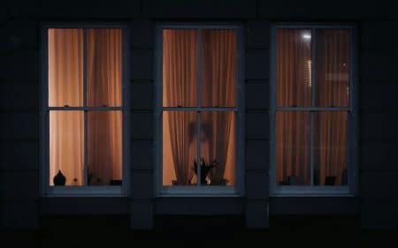 a dark room with three windows and curtains