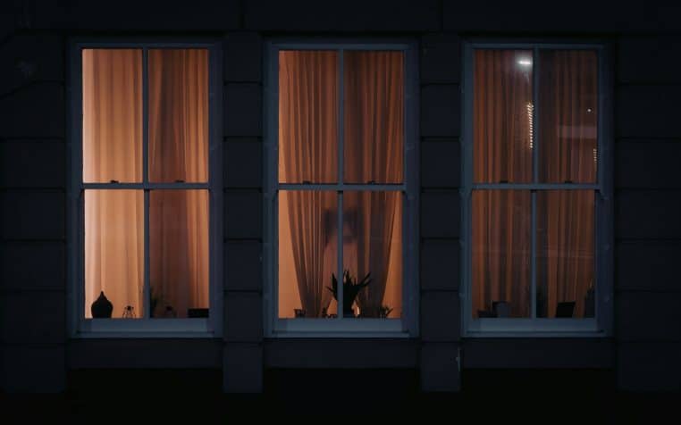 a dark room with three windows and curtains