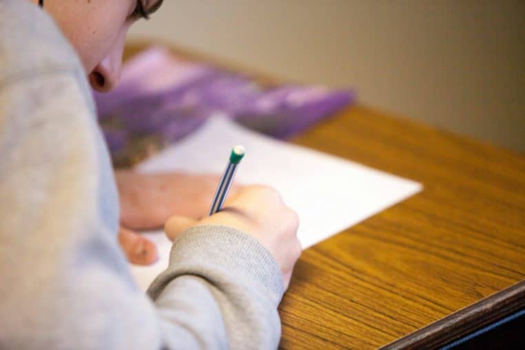 Main complétant une feuille OMR avec un crayon