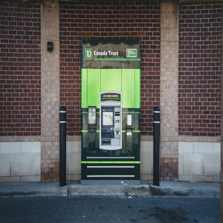 Distributeur automatique vert et noir devant un mur de briques