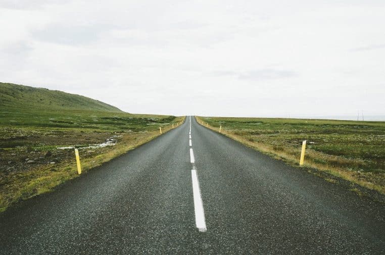 Vue frontale d’une autoroute déserte marquée par des bornes jaunes de part et d’autre de la chaussée.