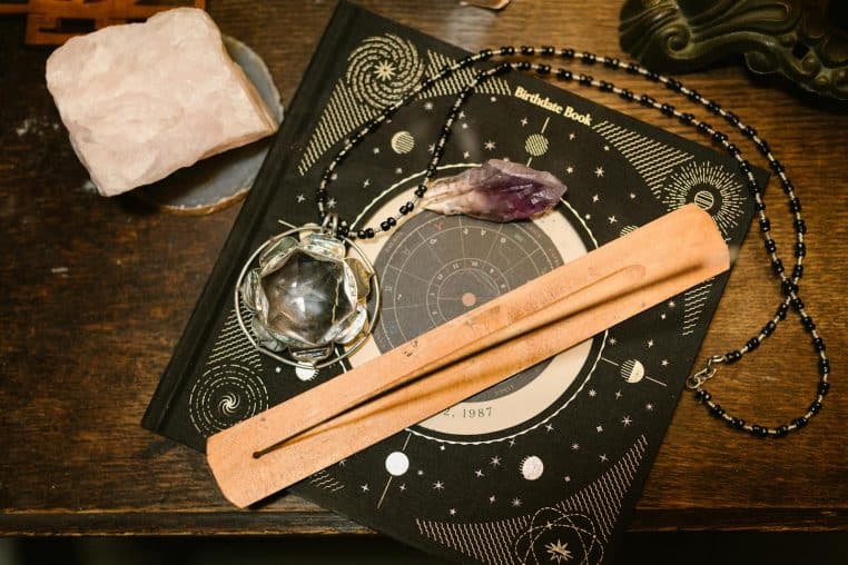 Top view of an astrology book, crystals, and incense holder for mystical ambiance.