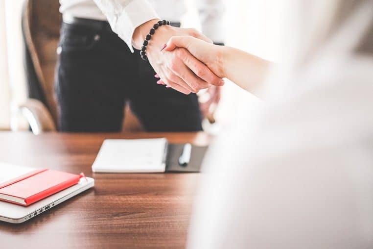 Un homme et une femme se serrant la main dans un bureau moderne.