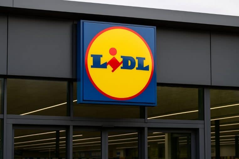 Logo Lidl au-dessus des portes vitrées d’une entrée sombre.
