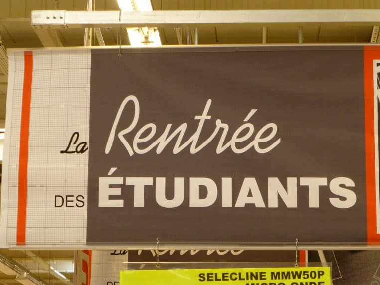 Trousse d’école bleue ouverte contenant des crayons de couleur alignés, une gomme et un cahier.