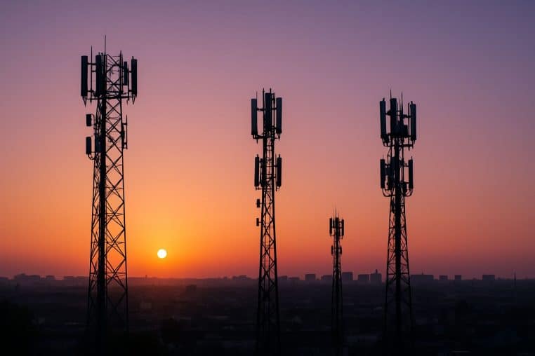 Antennes relais silhouettées au lever du soleil au-dessus d’une ville française.