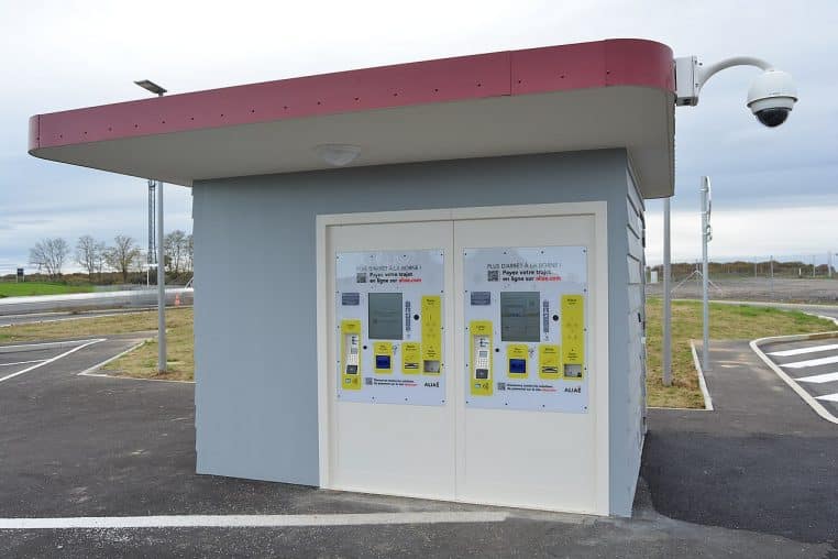 Bâtiment et bornes de paiement d’un péage sans barrières, parking vide.