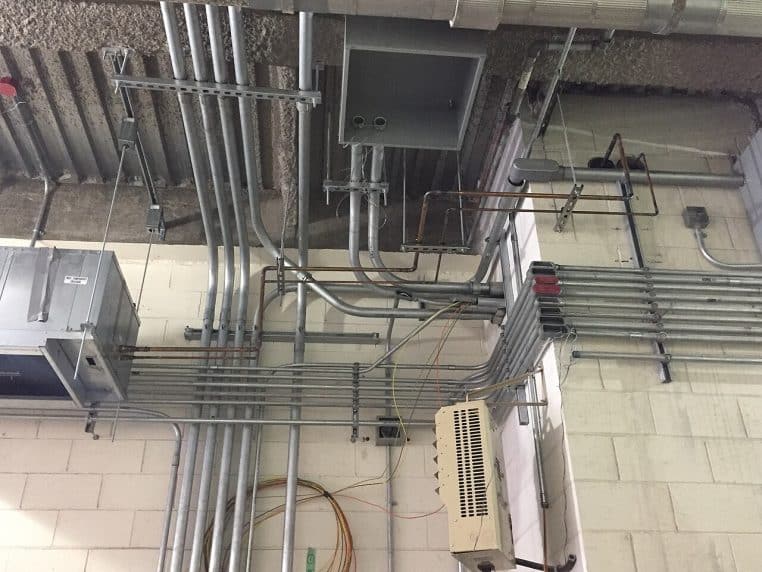 Vue rapprochée des conduits d’un système de climatisation dans un local technique.