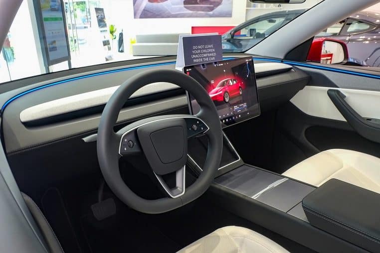 habitacle minimaliste avec volant et écran central d’une Tesla Model Y.
