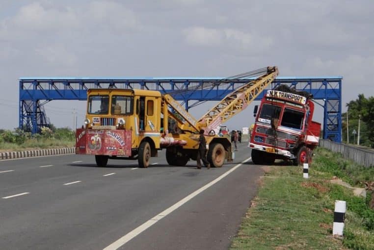 Camion renversé sur le bas-côté d’une autoroute et véhicule de remorquage.