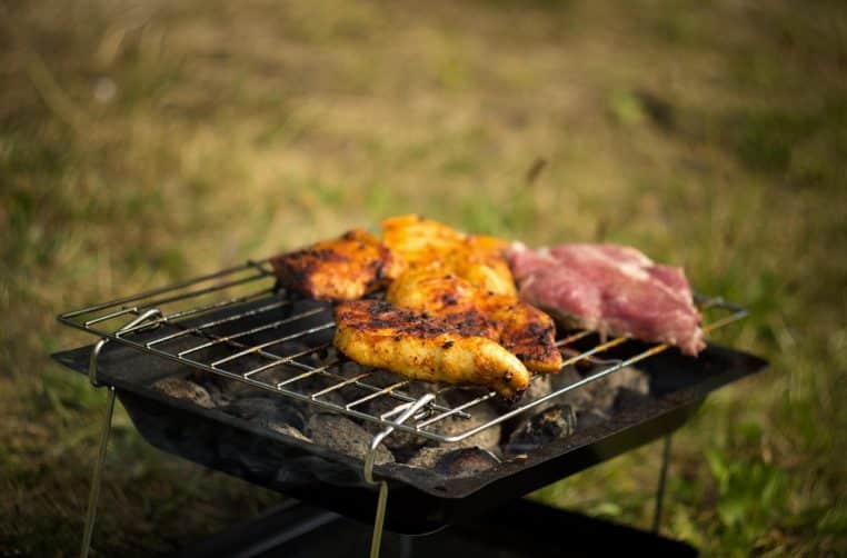 Morceaux de viande dorés sur grille en plein air.