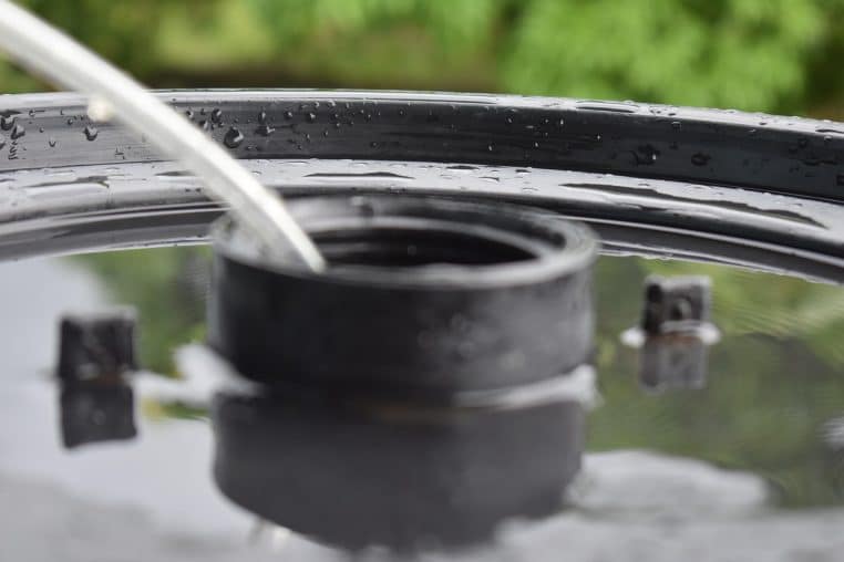 Tonneau et tuyau d’arrosage reliés à une réserve d’eau de pluie.