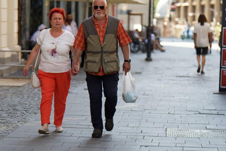 Couple de seniors marchant sur un trottoir urbain.