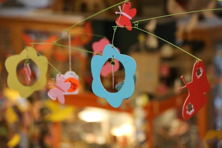 Mobile composé de fleurs en feutrine suspendu au-dessus d’un lit de bébé.