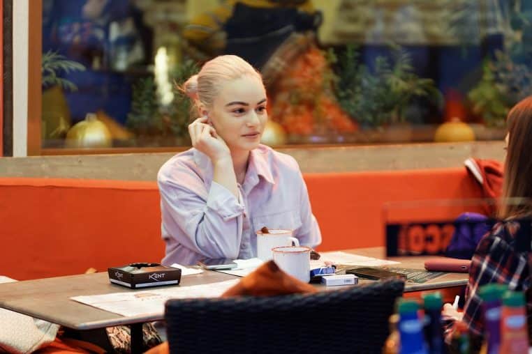 Femme blonde discutant autour d’une tasse de café.