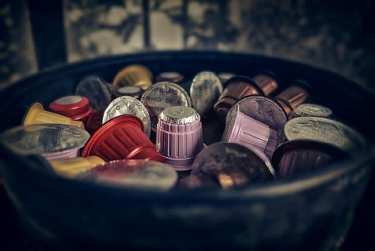 Capsules de café usagées de couleurs variées dans un seau en métal.