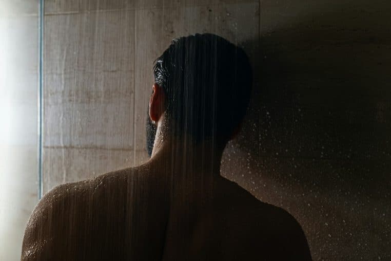 Homme prenant sa douche dans un endroit sombre.