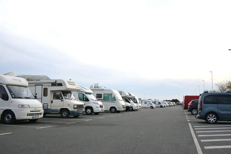 Camping‑cars garés sur un parking au bord de la mer.
