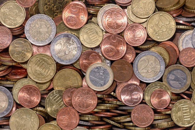 Pièces de 1 €, 2 € et centimes sur fond neutre flou.