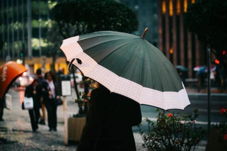 A person walks with an umbrella on a rainy day in São Paulo's urban environment.
