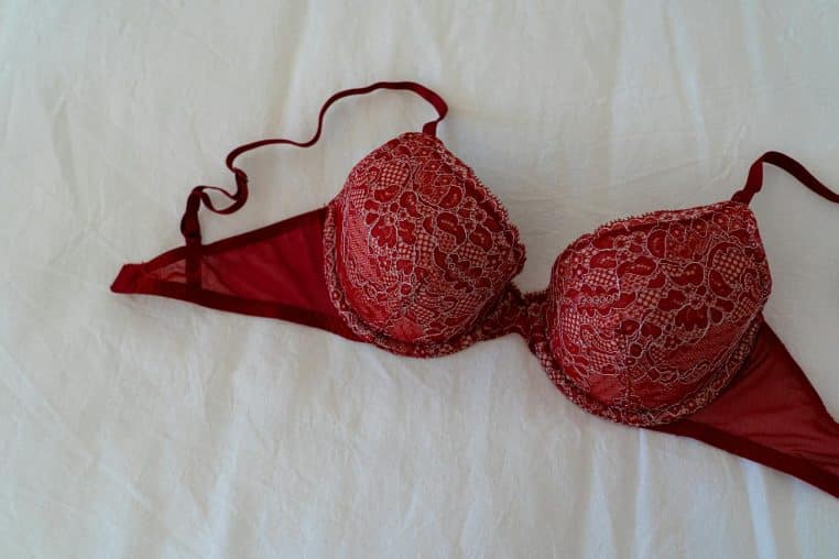 A stylish burgundy lace bra elegantly displayed on a white fabric background, offering a sense of luxury and intimacy.