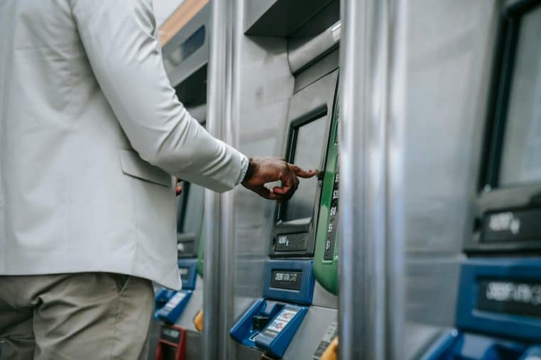 Side view of an adult using a self-service ticket machine indoors.